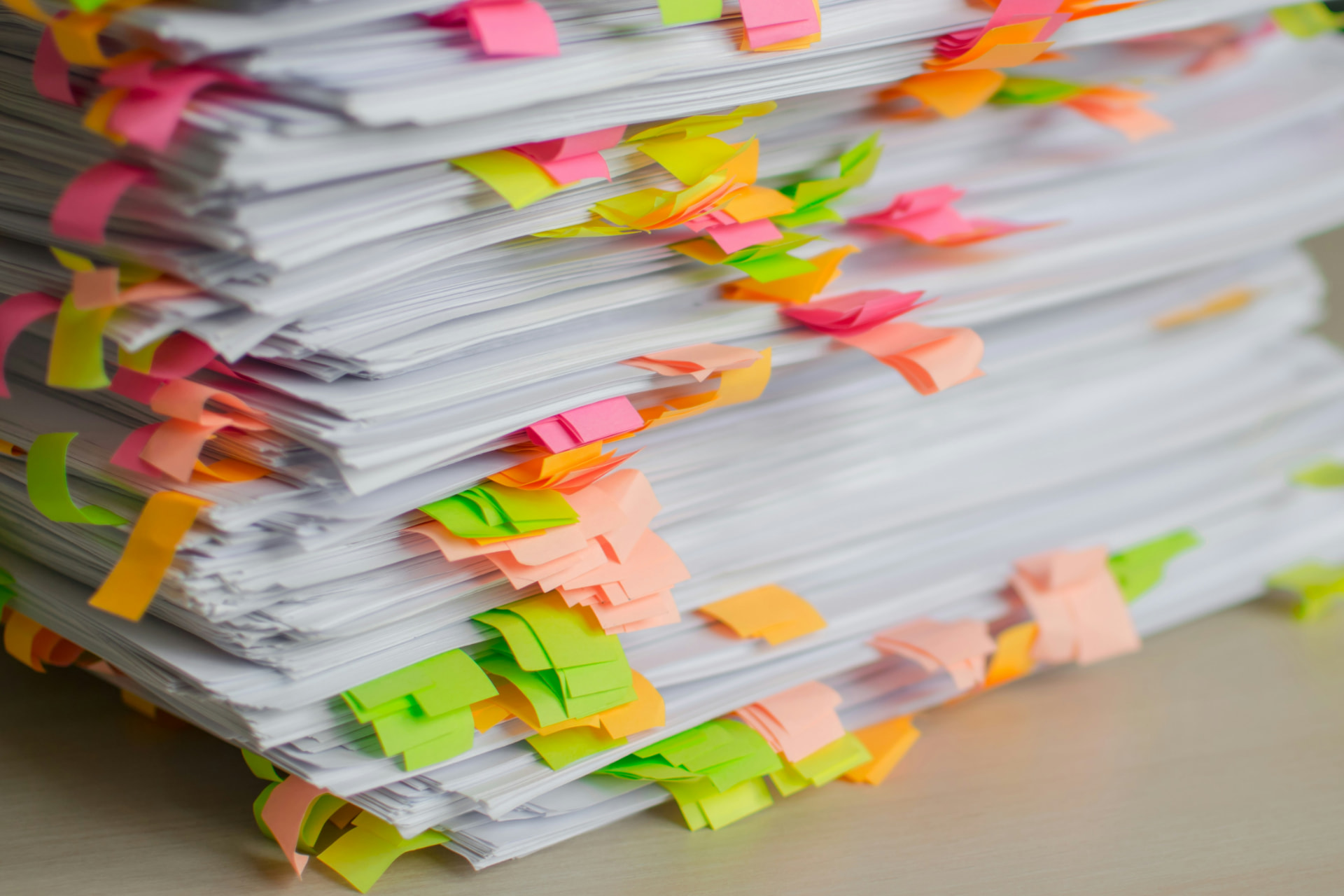 A tall stack of papers marked with colourful sticky notes