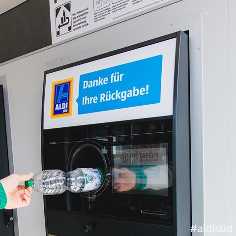 A hand inserting a plastic bottle into a bottle return machine at a German supermarket